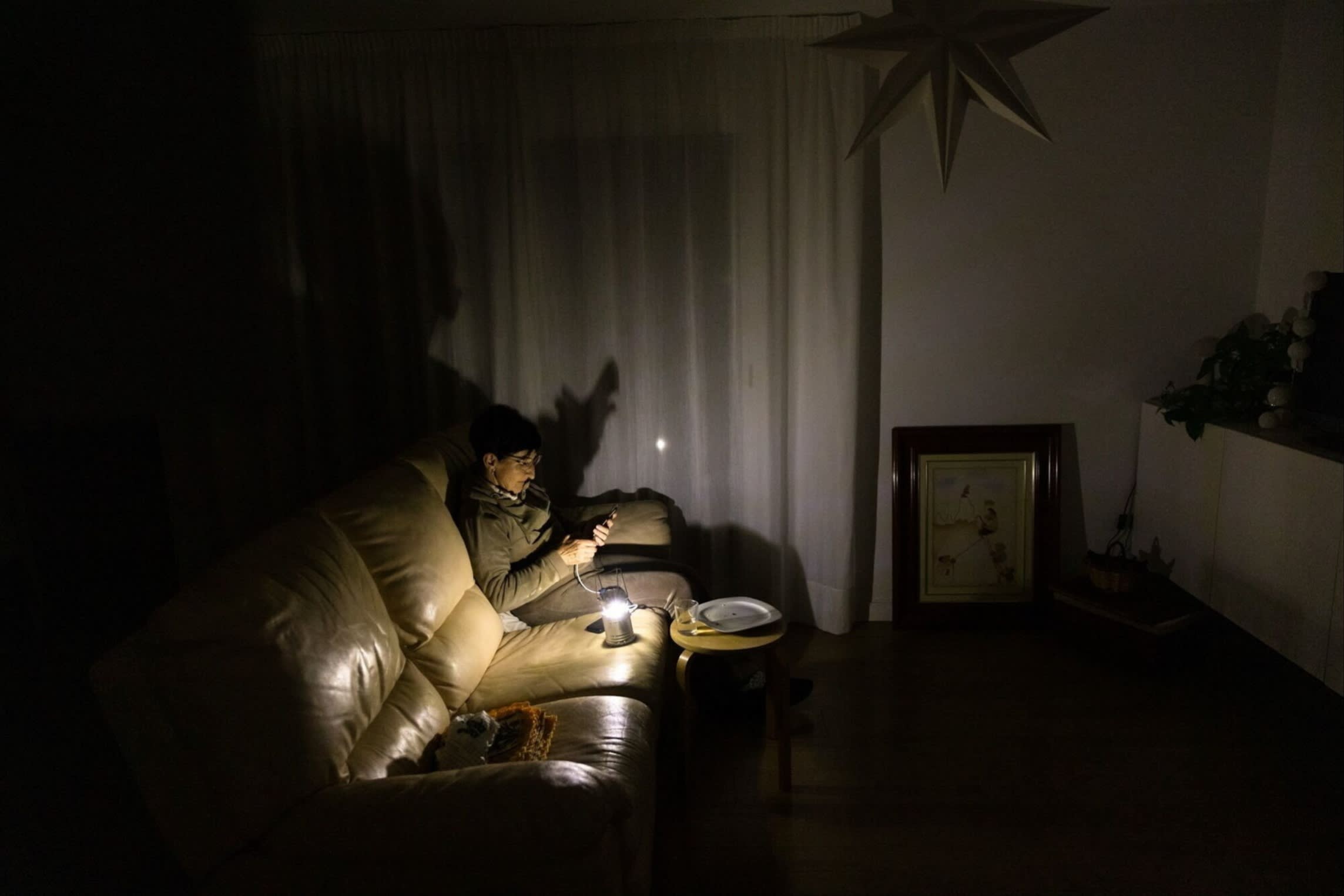 A resident uses a torch light in her home during a power outage in Molins de Rei, Spain,