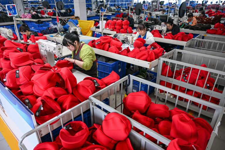 Employees work on a production line of caps that will be exported to the US