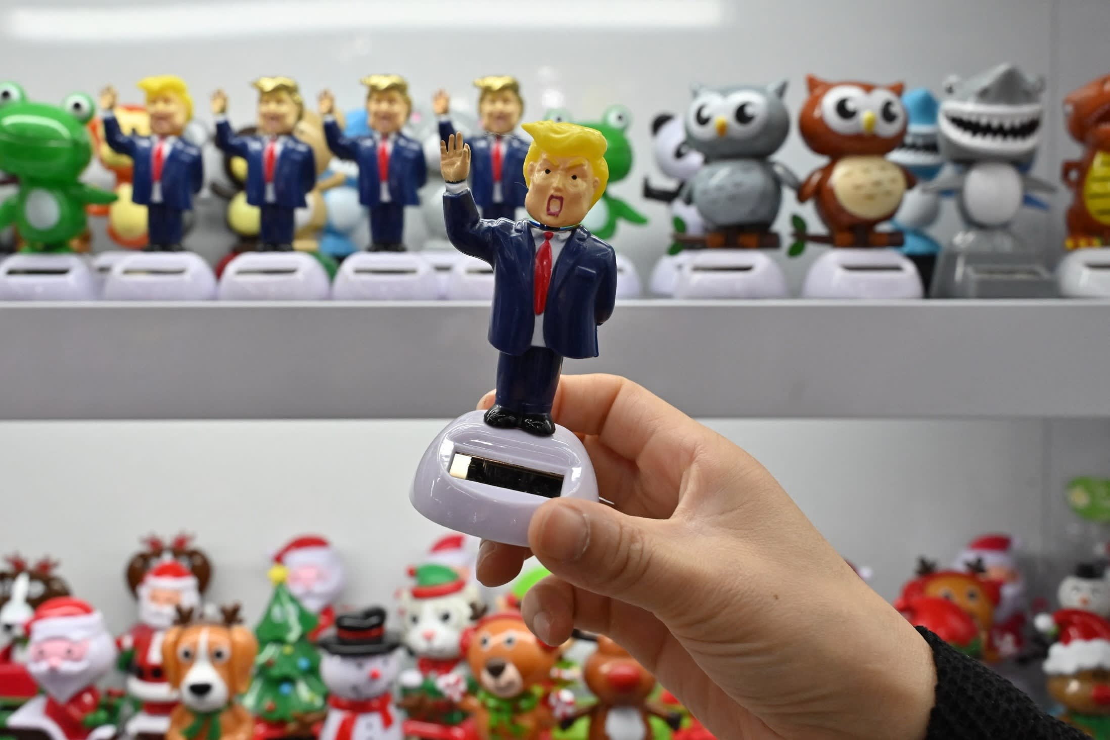 A shop owner holds a toy featuring US President Donald Trump at the Yiwu International Trade Market in Yiwu
