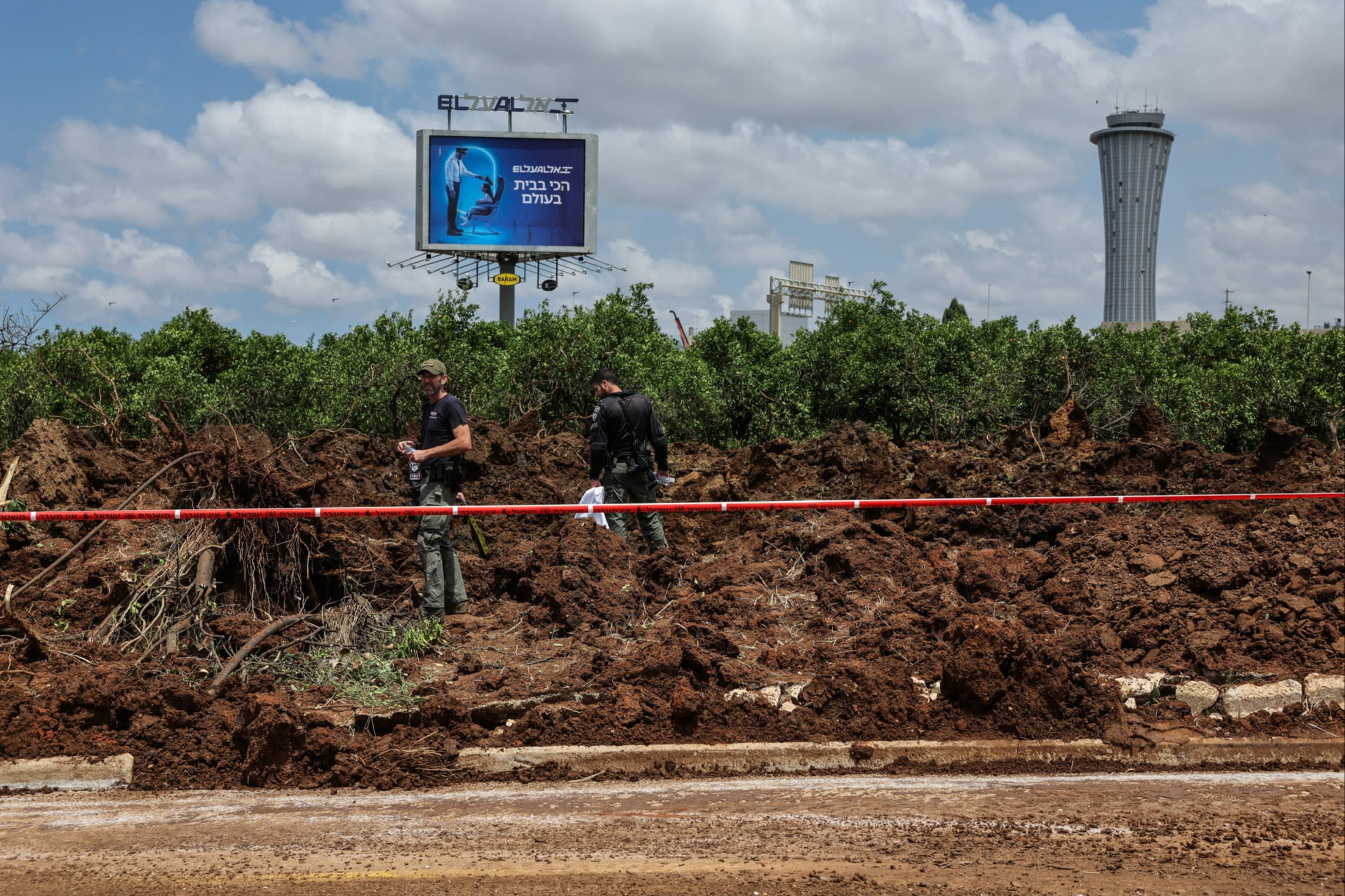 Israeli police officers investigate a crater at the site of a missile attack