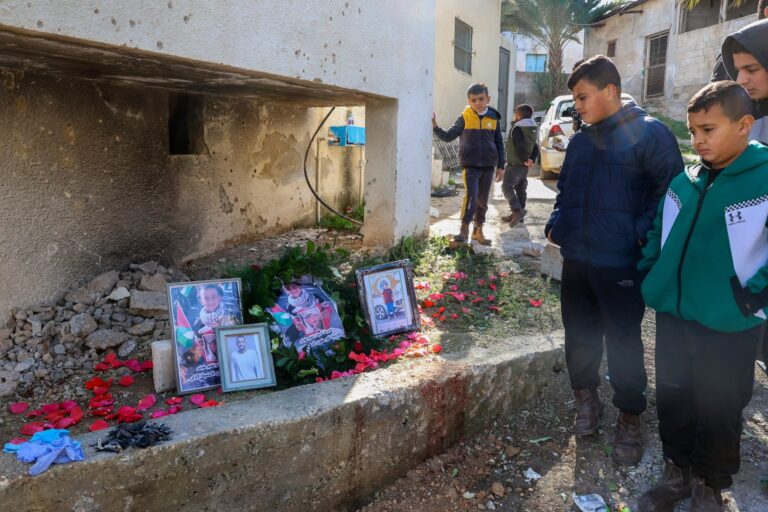 Friends and relatives look at pictures from left of Reda, Adam and Hamza Bisharat set up in memoriam at the site of the strike in their town of Tammun in the West Bank on January 9 2025