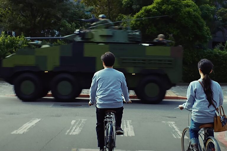 Still from Taiwanese TV show Zero Day showing cyclists and a passing military vehicle