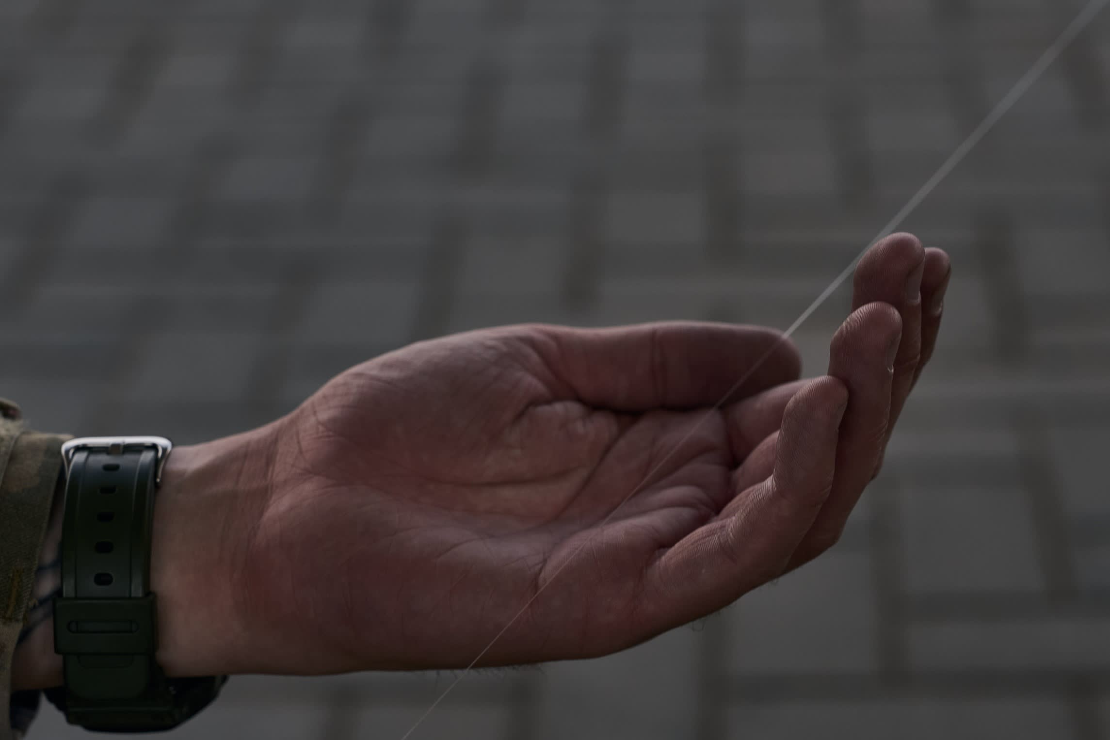 A soldier holds the wire from a kamikaze drone
