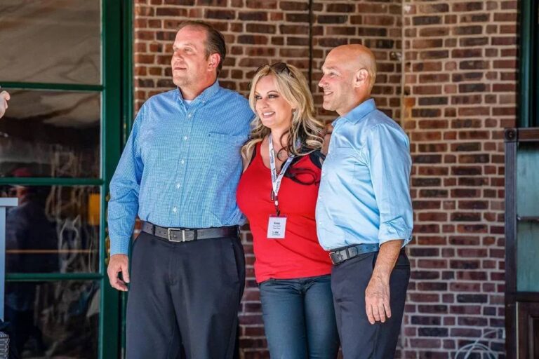 Stormy Daniels stands between two men for a photo