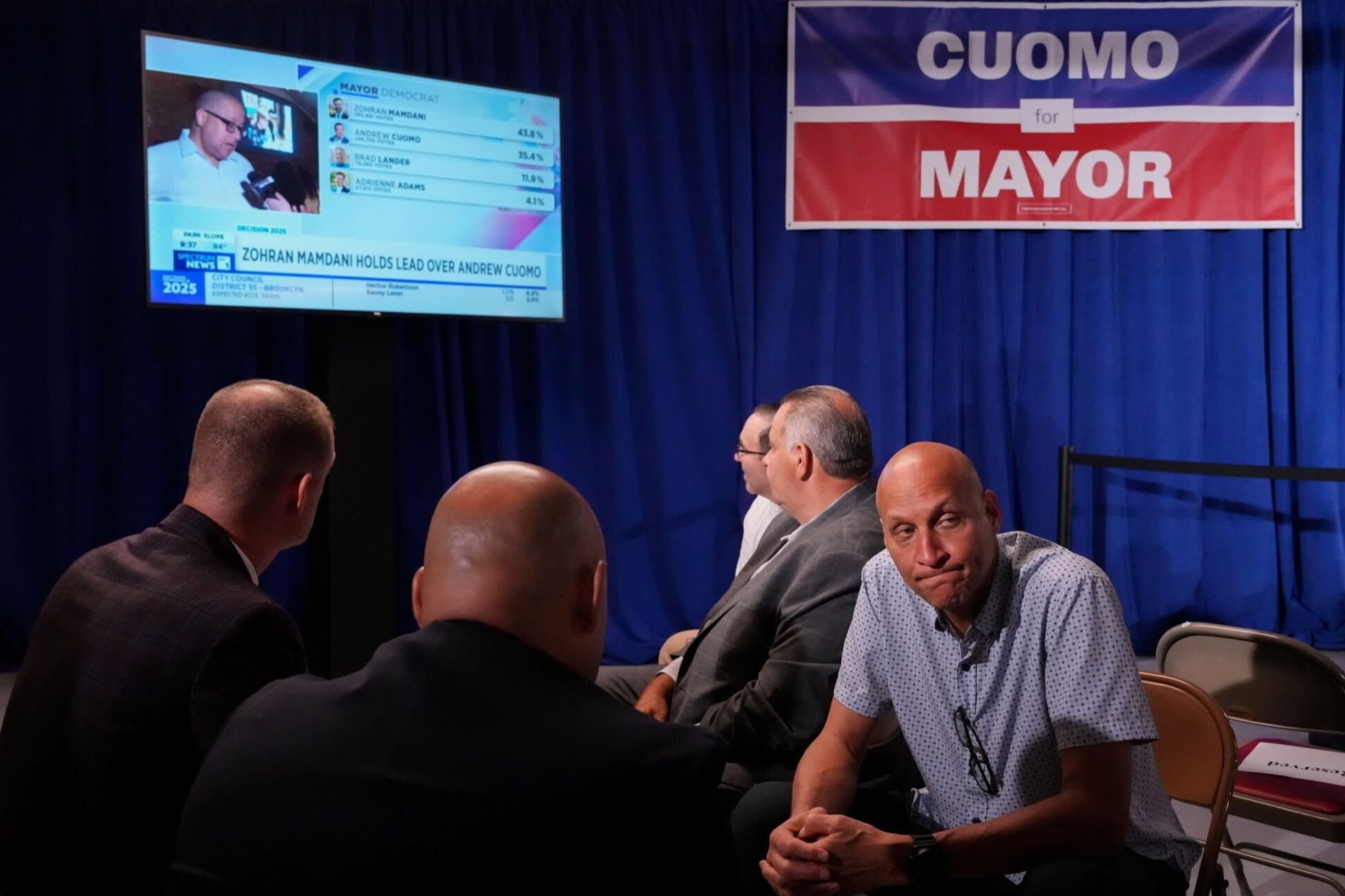 Attendees near a monitor displaying early election results during an election night event with Andrew Cuomo
