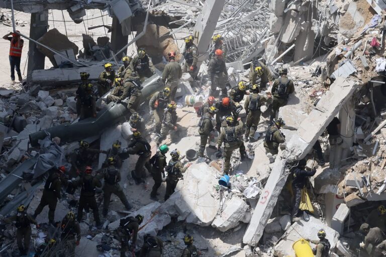 Israeli rescue workers search for missing people under the rubble of a partially collapsed residential building after Iranian missiles struck Bat Yam in central Israel on Sunday