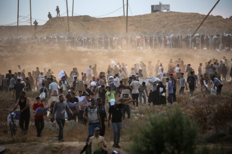 Members of a private US security company, contracted by the Gaza Humanitarian Foundation (GHF), a private US-backed aid group which the UN refuses to work with over neutrality concerns, direct displaced Palestinians as they gather to receive relief supplies at a distribution centre in the central Gaza Strip