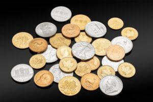 Gold and Silver bullion coins in a loose pile, on a dark background