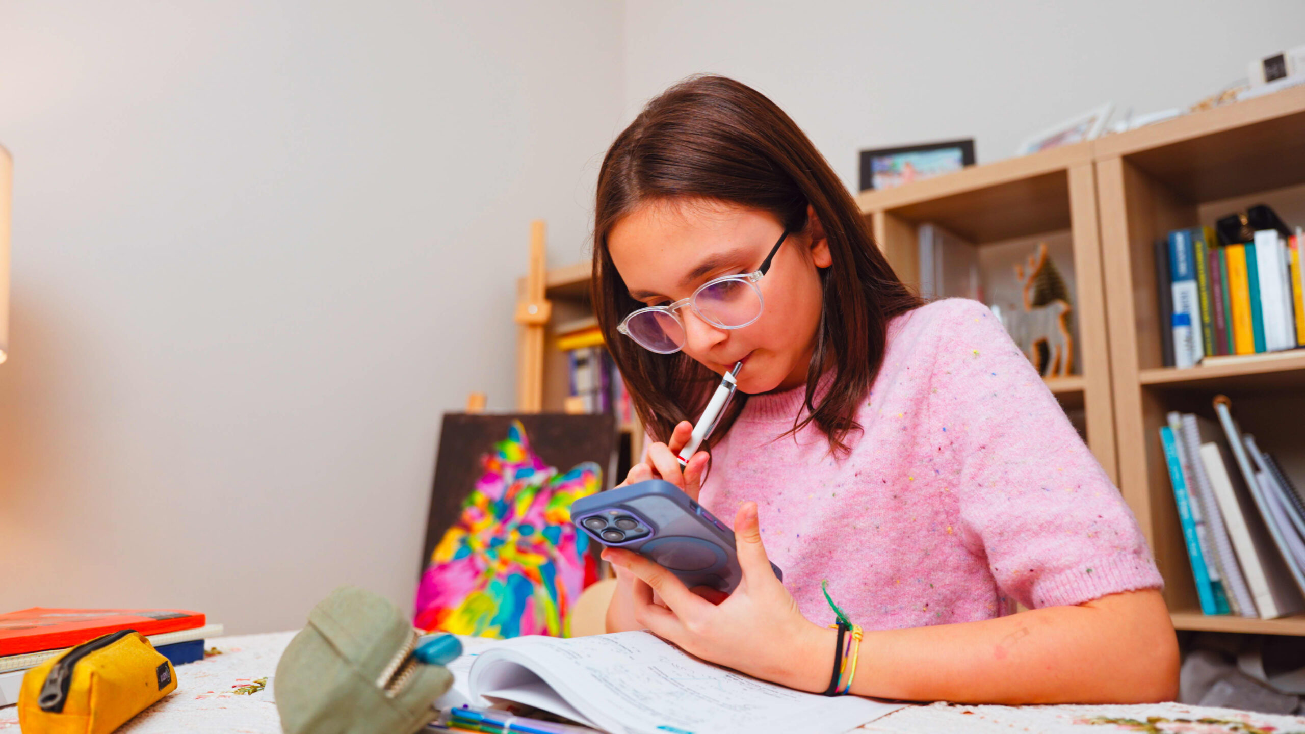 Preteen girl at desk solving homework with AI chatbot.