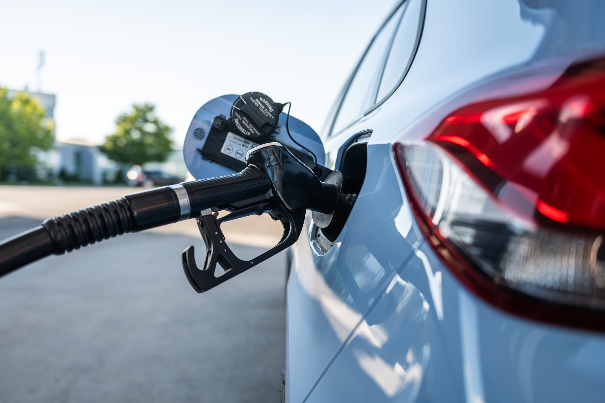 A fuel nozzle is inserted into a combustion engine at a petrol pump at a filling station during a refueling process.