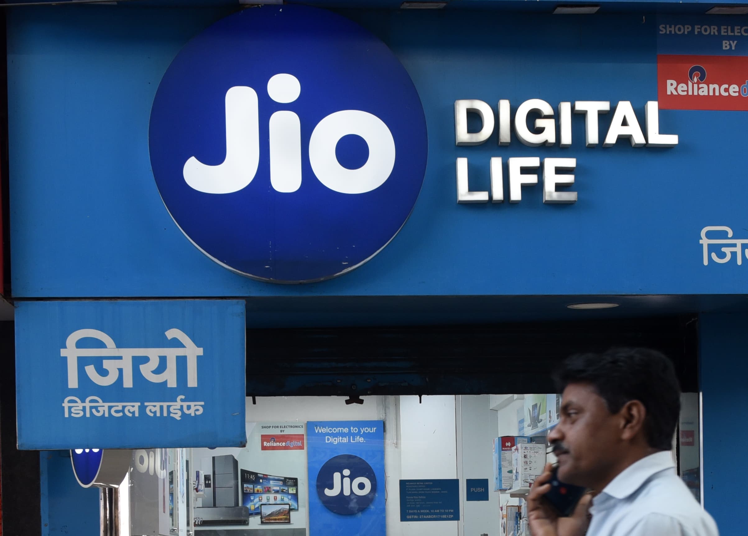 A man talks on his phone walks past a Jio store in Mumbai, India, 22 March, 2023. Reliance Jio rolls Out 5G Services in 41 More Cities, Network Now Live in 406 Cities in India according to an Indian media report.