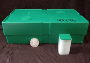 Green cardboard Silver Eagles monster box showing mint markings with individual storage tube and one-ounce coin displayed for size comparison.